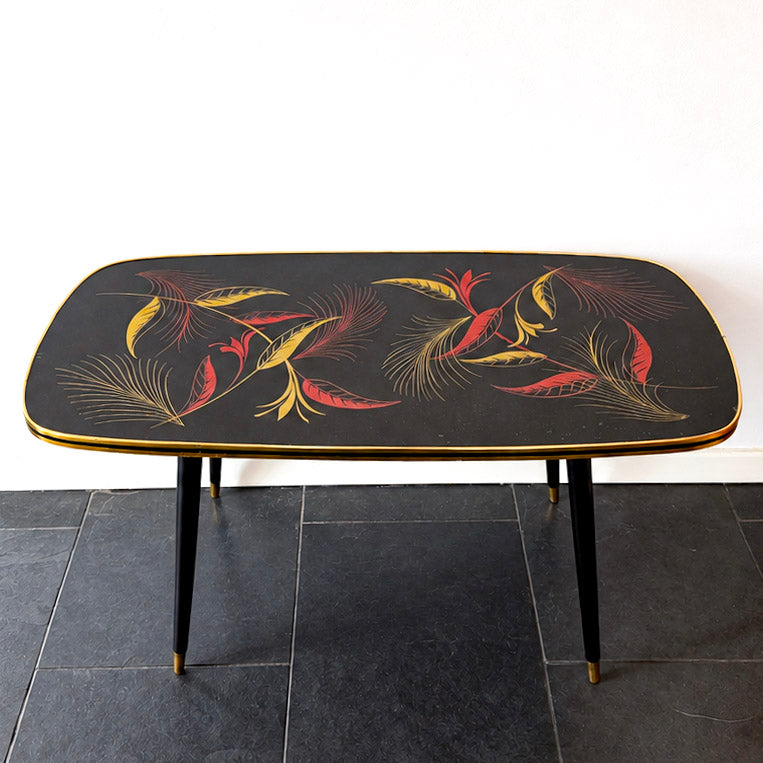 Mid-Century Modern coffee table, black Formica with red and gold botanical motif, wood and brass.