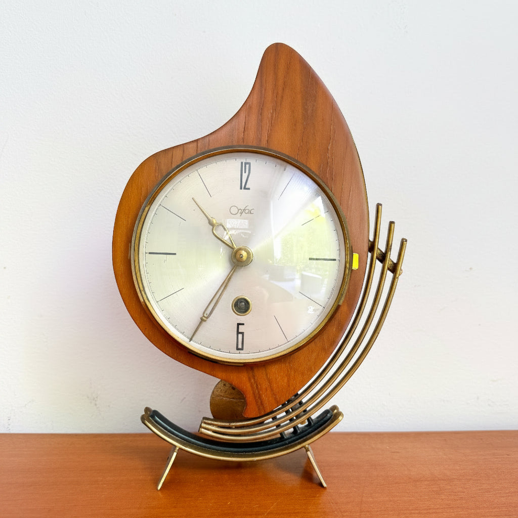 Mid-century modern Orfac mantel clock in wood and brass-toned metal with atomic-style form and pendulum.