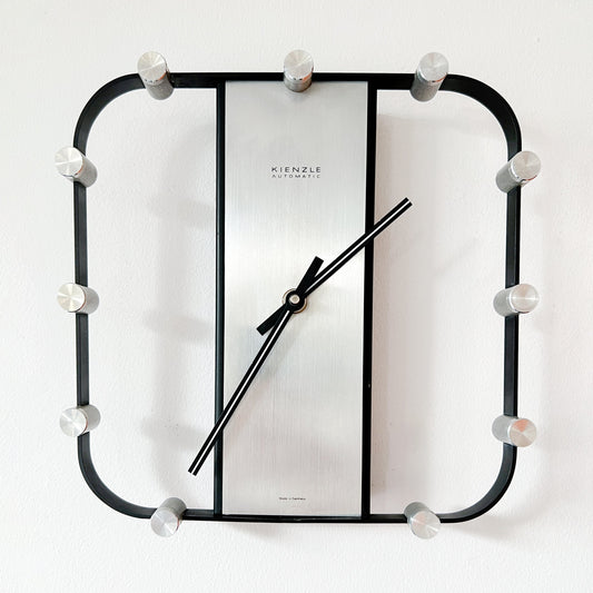 Mid-Century Modern Kienzle wall clock with silver dial and black frame.