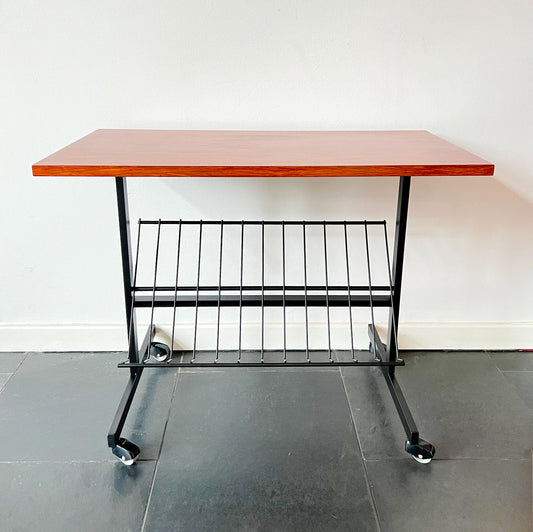 Mid-Century Modern wheeled table with wooden top and black metal frame, magazine rack beneath, vintage.