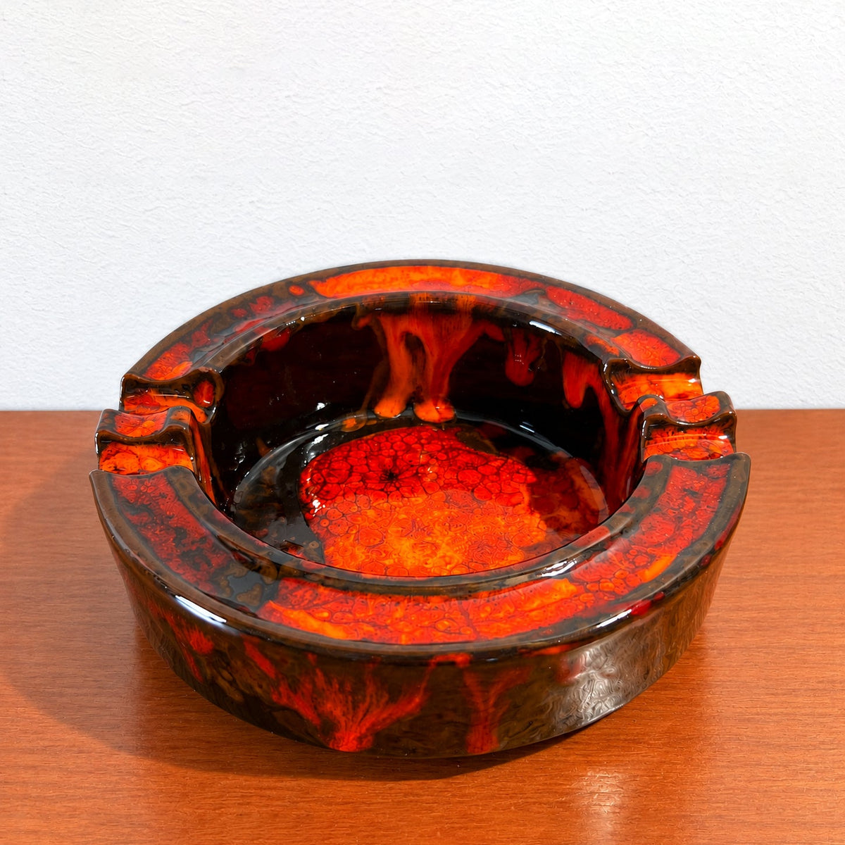 Mid-Century Modern fat lava ceramic ashtray in red, orange and dark brown glaze.