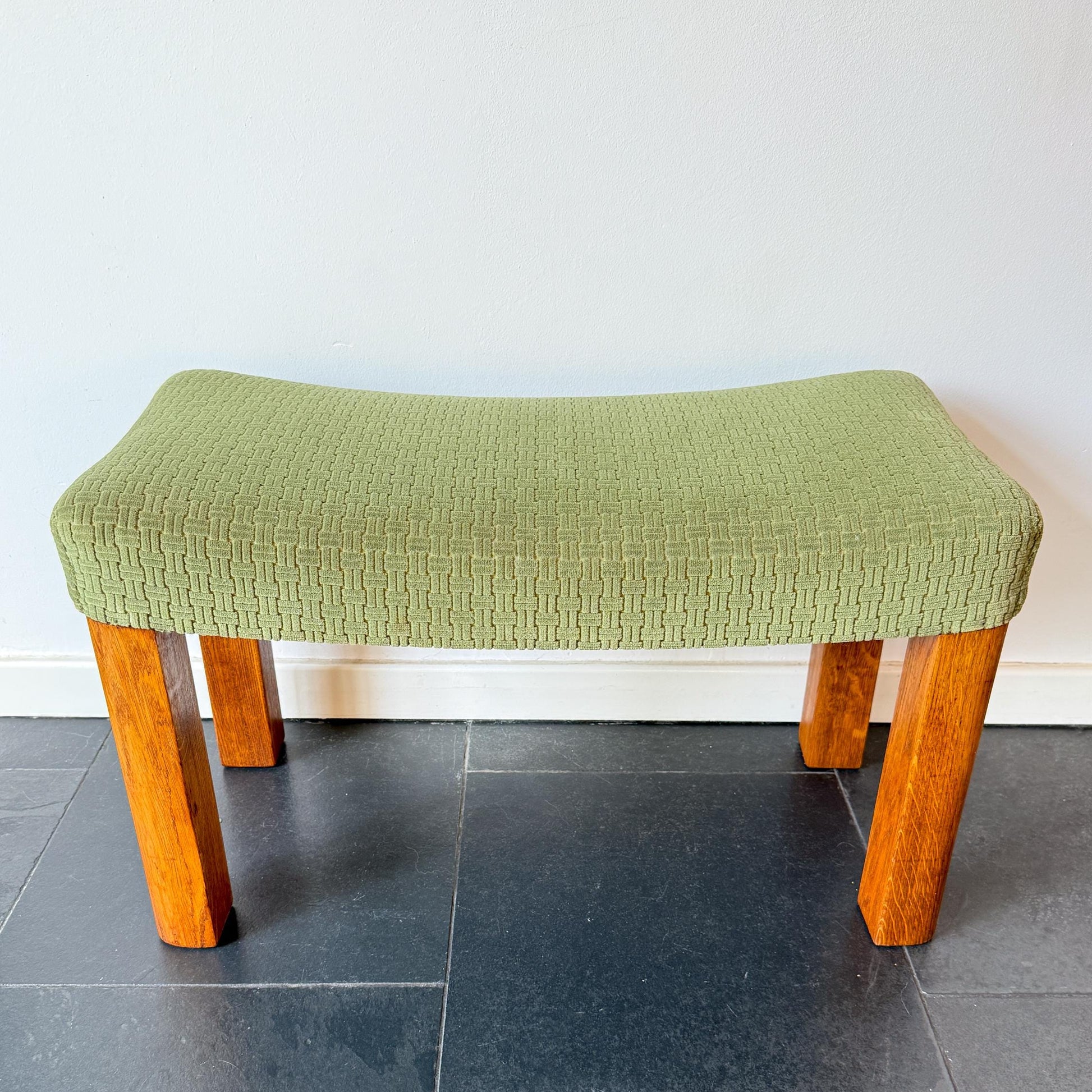 Mid-century modern wooden footstool with green upholstered seat.