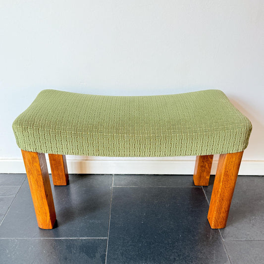 Mid-century modern wooden footstool with green upholstered seat.