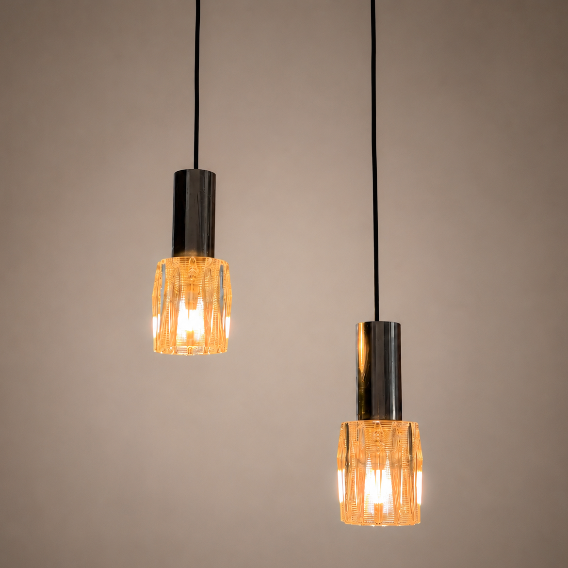 Mid-Century Modern pendant lights with textured pressed glass shades and chrome-plated fittings.